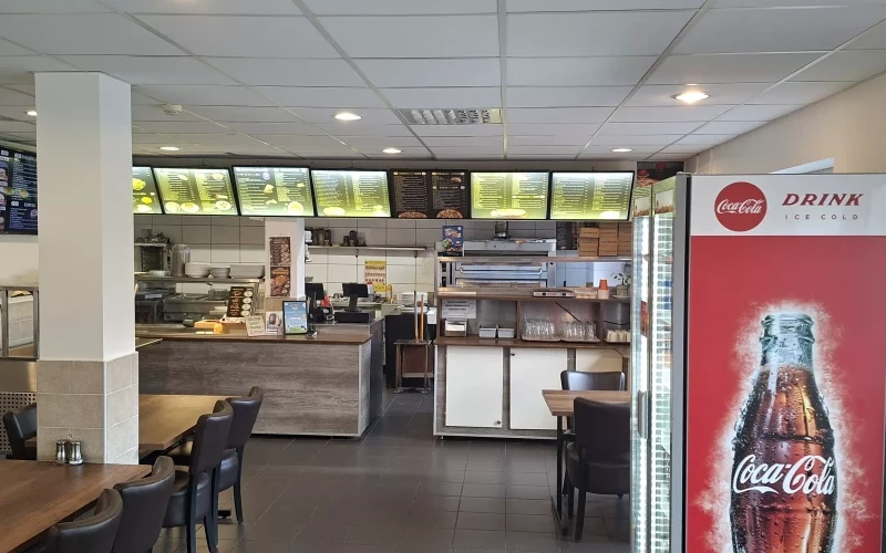 Kassadisk och menybord med röda accenter i pizzerian i Åkersberga