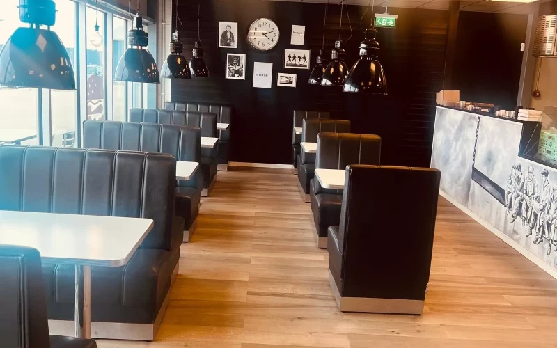 Väldesignad matsal med mörka bås och industriella pendellampor på Burgeriet nära Södertälje