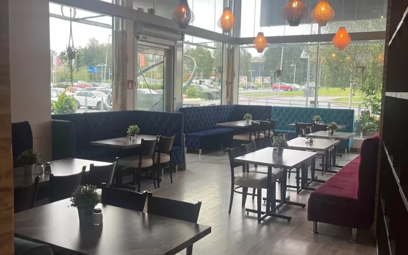Ljus matsal med stora fönster och mörka stolar i pizzerian i Haninge