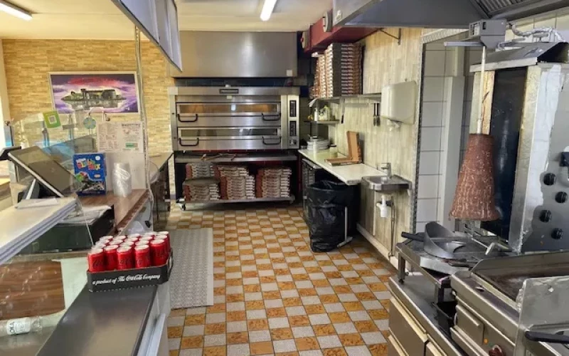 Välutrustat kök med disk och kaklat golv i pizzeria med grill i Vaxholm